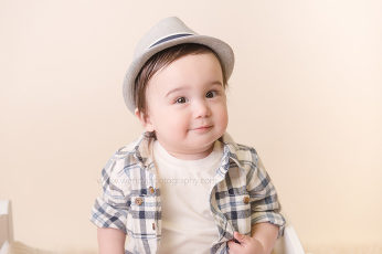 Cute baby boy wearing a hat during a baby portrait session by Wendy J Photography.