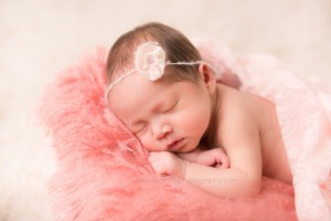 Sleeping newborn girl posed on blanket.