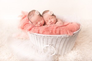 Newborn twins posed in white basket for portrait session.