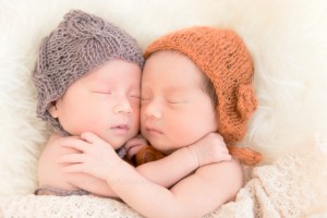 Sleeping newborn babies embrace in a fine art portrait photo session.