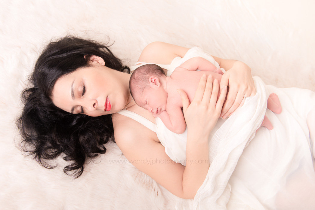 Fine art portrait of sleeping newborn baby girl with her mother.
