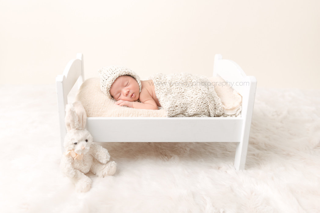 Newborn baby girl sleeping on a cute dolls bed.