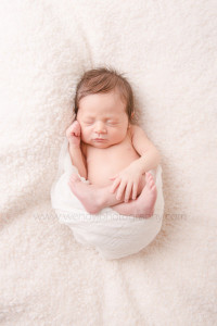 Sleeping newborn baby girl, wrapped in white cloth.